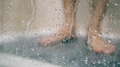back view of attractive african american woman with sponge taking shower