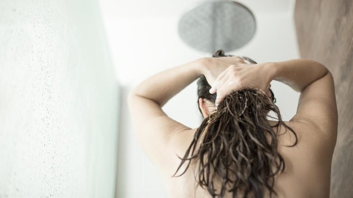 back view of attractive african american woman with sponge taking shower