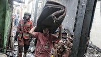 Warga membawa barang-barang yang masih bisa diselamatkan.