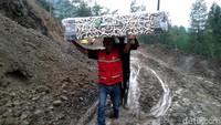 Untuk memenuhi kebutuhan ekonomi warga, barang dipanggul saat melintas di titik longsor. Hanya beberapa warga yang bisa melintas dengan mengendarai sepeda motor.