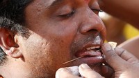 Salah seorang pria dari suku Tamil mengaitkan sebuah benda tajam ke lidah dalam ritual Thaipusam yang diselenggarakan di Batu Caves, Kuala Lumpur, Malaysia, Senin (21/1/2019).