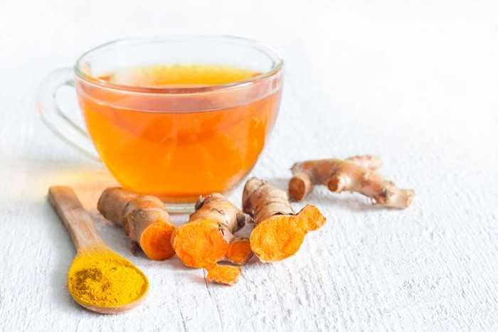 Raw roots of tumeric and tea on white planks detox concept closeup