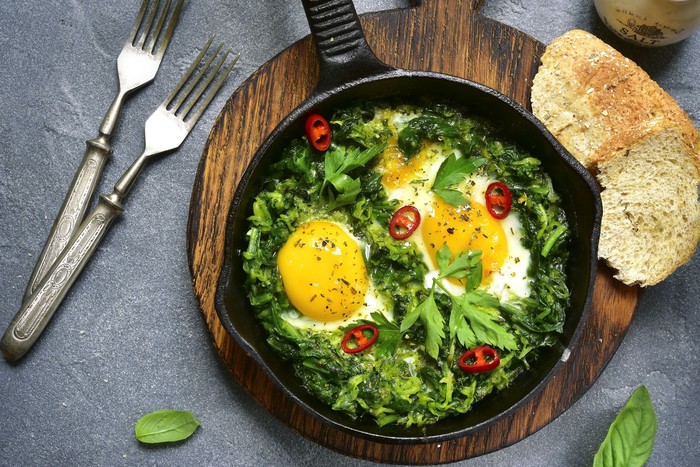 bayam Green shakshuka in a cast iron pan on a grey slate,stone or concrete background.Top view.