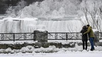 Pengunjung memotret Air Terjun Niagara yang berubah menjadi hamparan es. Moe Doiron/Reuters.