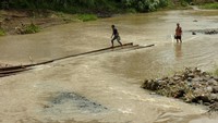Dua warga menyeberangai Sungai Kemisik samping jembatan yang ambruk di Desa Wanasari, Kabupaten Tegal, Jawa Tengah, Rabu (23/1/2019). ANTARA FOTO/Oky Lukmansyah.