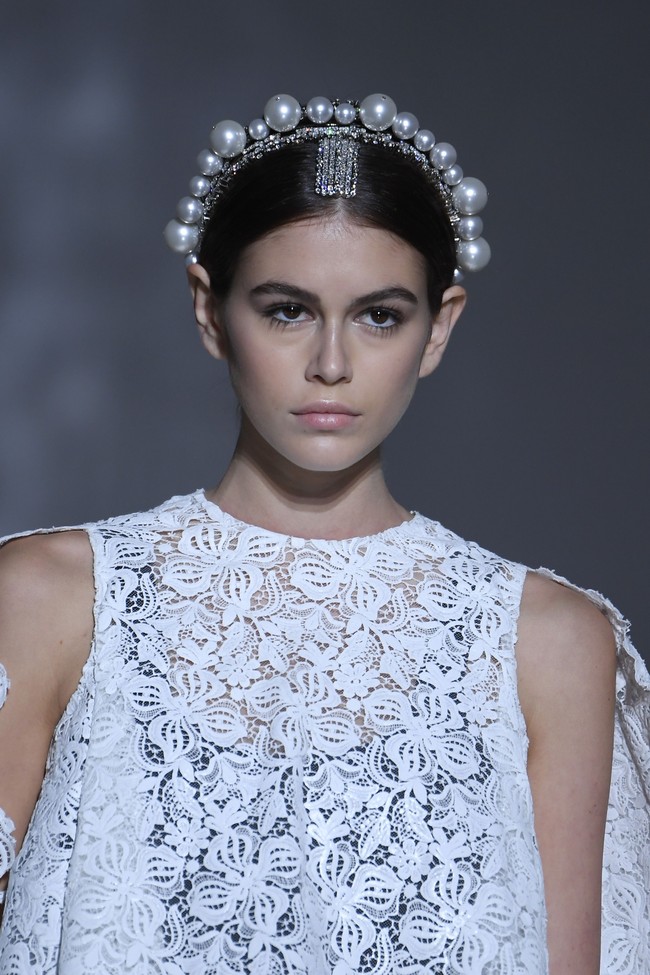 Koleksi adibusana terbaru Givenchy yang membungkus tubuh Kaia Gerber berupa atasan putih berbahan lace dalam siluet A yang jatuh di atas paha. Bergaya sleeveless atau tanpa lengan, busana tersebut dilengkapi sayap yang menjuntai dari bahu. (Foto: Getty Images)