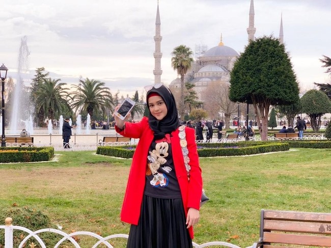 Setelah beribadah umrah, Cut Meyriska juga mengunjungi Turki. Saat berjalan-jalan di sana, ia tampil cantik memakai hijab bergaya kasual. Ia memadukan T-shirt Mickey Mouse dengan coat warna merah dan rok pleats. Foto: Instagram/CutRatuMeyriska