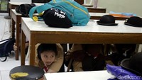 Siswa bersembunyi di bawah meja belajar untuk menyelamatkan diri saat terjadi gempa.