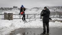 Para pengunjung pun tak melewatkan kesempatan untuk berfoto dengan latar Air Terjun Niagara yang membeku. Moe Doiron/Reuters.