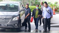 Khamami terlihat mengenakan kaos polo warna hijau dibalut jaket warna hitam.