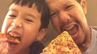 Pizza dan Nintendo party, tulis Angga dalam akun Instagramnya. Bersama si kecil, keduanya sama-sama menikmati pizza yang renyah. Foto: Instagram@anggapuradiredja