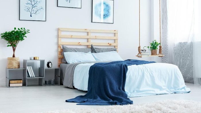 Simple bedroom with double bed, blue bedding, posters and window