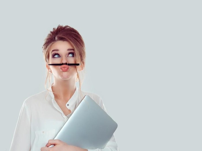 Annoyed woman, funny student with laptop computer playing holding pen between nose and lips as mustache looking up thinking playful bored after working long hours isolated light blue white background