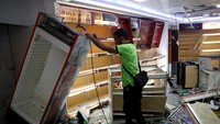 Seorang pekerja berusaha merapikan toko yang hancur dijarah massa. REUTERS/Carlos Garcia Rawlins.