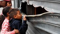 Seorang anak melihat sebuah toko yang hancur dirusak massa di Caracas, Venezuela, Kamis (24/1) waktu setempat. REUTERS/Carlos Garcia Rawlins.
