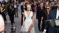 Lady Gaga tampil mengenakan gaun putih karya Dior berjalan di karpet perak ala Marilyn Monroe. Foto: Rodin Eckenroth/Getty Images