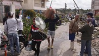 Warga mengumpulkan beragam berharga milik mereka untuk diselematkan ke tempat yang lebih aman, sementara rumah mereka sebagian telah hancur dihantam tornado. Fernando Medina/Stringer via Reuters.