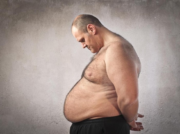 Overweight woman with tape is measuring fat on belly - obesity concept
