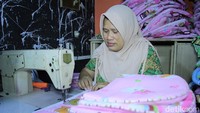Ela melakukan proses makloon jahit gendongan bayi di ruangan tengah rumah miliknya.