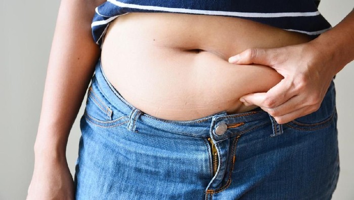 Overweight woman with tape is measuring fat on belly - obesity concept