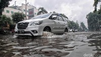 Sejumlah kendaraan masih melintasi Jalan Bukit Gading Raya meski terendam banjir.