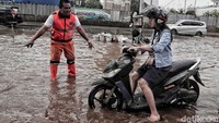Para petugas Penanganan Prasarana dan Sarana Umum DKI Jakarta atau Pasukan Oranye terjun langsung ke lokasi untuk membantu mengatasi lalu lintas yang macet akibat banjir.