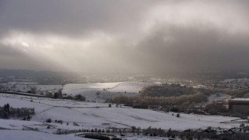 Sinar mentari menembus barisan awan, menuju hamparan salju di dekat Oldham, Inggris. (Foto: Anthony Devlin/Getty Images)