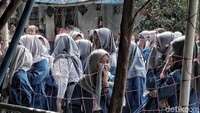 Para siswa sekolah dikumpulkan di tengah lapangan saat proses fogging dilakukan.