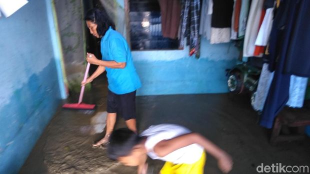 Warga membersihkan lumpur yang masuk rumah
