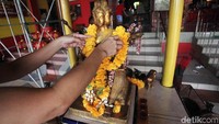 Patung dewa dihiasi dengan rangkaian bunga.