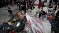 Seorang warga bergegas menuju kereta untuk mudik di Stasiun Beijing. Thomas Peter/Reuters.