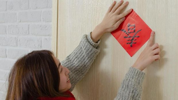 dekorasi imlek Young asian woman pastes spring couplet. It is the tradition of Chinese culture to stick spring couplet to the doors for Chinese New Year. The word on the spring couplet means