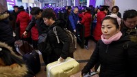 Warga bergegas membawa barang-barang mereka untuk menaiki kereta di Stasiun Beijing. Thomas Peter/Reuters.