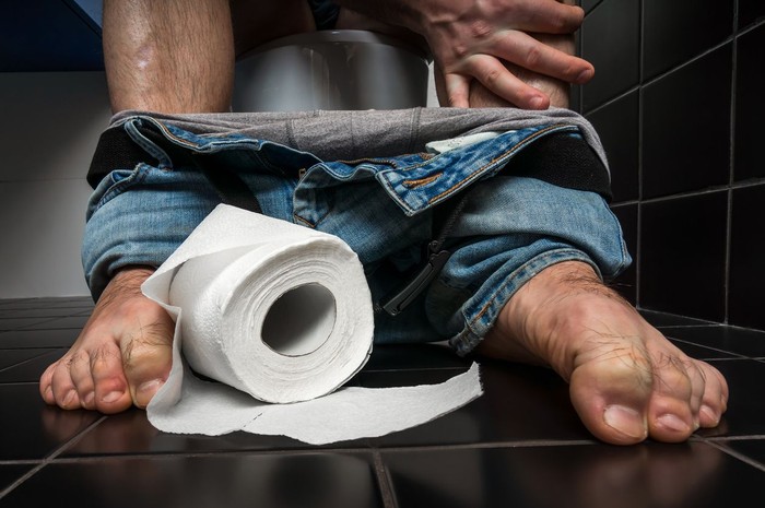 toilet mules diare konstipasi bab Man suffers from diarrhea is sitting on toilet bowl and toilet paper roll near his legs - diarrhea concept
