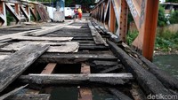 Salah satu bagian pijakan jembatan kayu telah lapuk dan bolong sehingga membahayakan para pengguna yang melintasi jembatan tersebut.