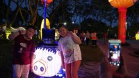 Anak-anak berfoto dengan latar belakang beragam lampu hias warna-warni dan berbagai bentuk di Malaysia. Istimewa/Yam G-Jun/AP Photo.