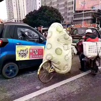 Ketika udara sedang dingin-dinginnya tapi kamu harus pergi dengan sepeda. Maka bersepeda sambil berselimut tebal menjadi solusi. Kenapa tidak? (Foto: Instagram/boredpanda)