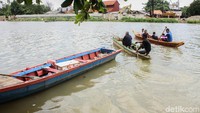 Warga menggunakan dayung kayu untuk menggerakan sampan.