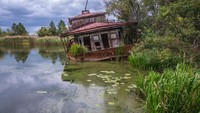 Suatu rumah penduduk di pinggir danau yang ditinggalkan (iStock)