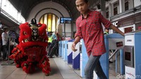 Seorang warga yang takut tampak mempercepat langkahnya saat melihat barongsai beratraksi di pintu masuk peron.