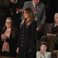 Melania menjatuhkan pilihannya kepada blazer yang nampak seperti gaun berhias kancing perak. Siluet busana yang tegas ini datang dari rumah mode Inggris, Burberry. Foto: Getty Images
