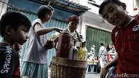 Seorang tukang jamu gendong melayani anak-anak di kawasan Glodok, Jakarta Barat.