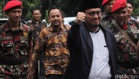 Dahnil mengenakan jaket berwarna hitam dan berpeci. Dia hanya tersenyum saat ditanya wartawan.