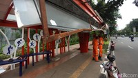 Petugas PPSU bergotong-royong memperbaiki halte.