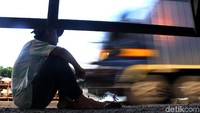 Seorang remaja menunggu untuk berpindah truk agar dapat melanjutkan perjalanan.
