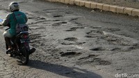 Pemotor melintas di jalur Pantura yang berlubang.