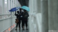 Beberapa warga saat menyebrang JPO tampak tertiup angin kencang.