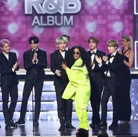 Meskipun berbusana formal, BTS tetap menampilkan gaya eksentrik yang sudah jadi ciri khas mereka. Yakni rambut berwarna mencolok seperti lavender, minty green, ashy gray dan cokelat keemasan yang kontras dengan setelan jas hitam-hitam mereka. Foto: Rich Fury/Getty Images