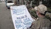 Satpol PP menurunkan baliho yang dipasang di pinggir jalan di kawasan Sunter, Jakarta Utara.