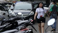 Seorang warga melintas sambil menenteng bunga mawar yang akan dihadiahkan kepada pasangannya.